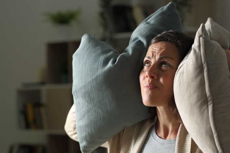 An Angry Woman Holding Pillows To Her Ears