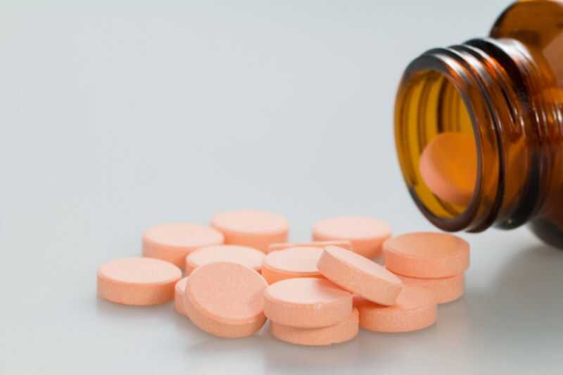 A Medicine Bottle Spilling Pills On A White Surface