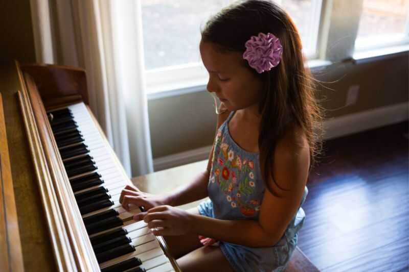 A Young Girl Playing An Upright Piano