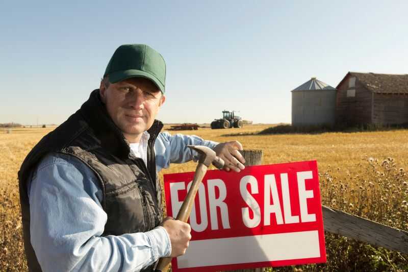 A Man Next To A For Sale Sign On A Farm