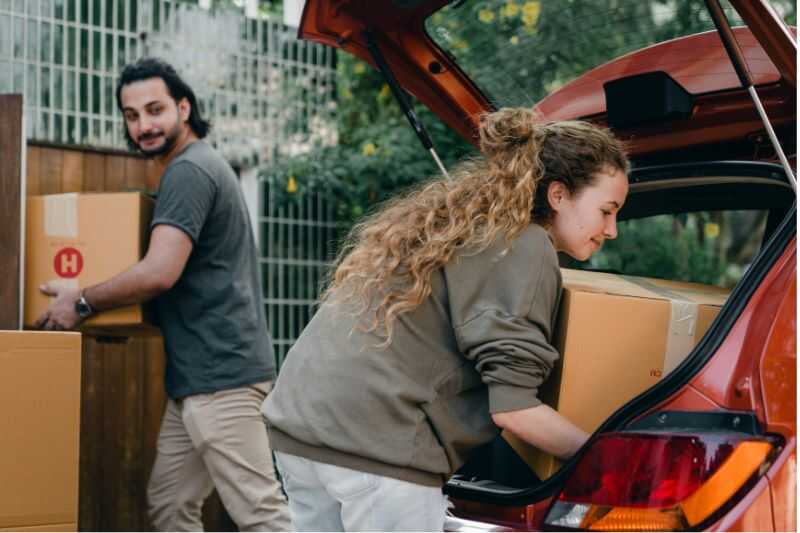 A Woman Loading Boxes Into A Car