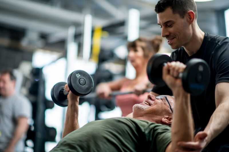 An Older Man Lifting Weights At The Gym