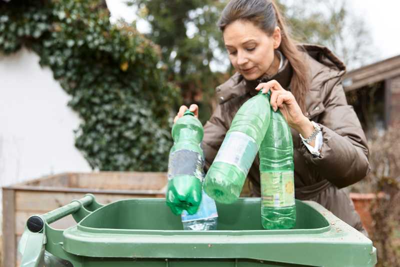 A Woman Recycling Green Plastic Bottles