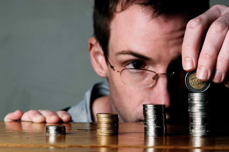 A Man Arranging Various Coins Into Piles In Order To Count Them