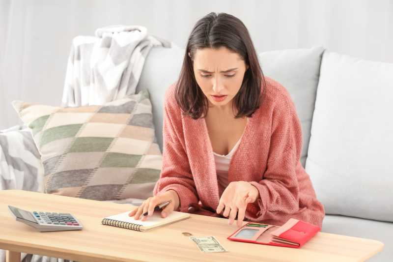 A Young Woman With A Worried Expression Calculating Finances